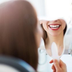 Patient smiling at reflection in tooth-shaped mirror