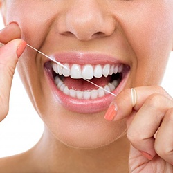 Close up of woman smiling and flossing after dental bridge restoration