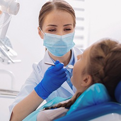 A female dentist examining a woman’s smile to determine if she’s a qualified candidate for ClearCorrect