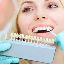 Woman's smile compared with tooth color chart before dental bonding