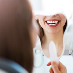 Woman looking at her smile in the mirror after gum recontouring