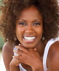 Woman smiling leaning on hands after dental crown restoration
