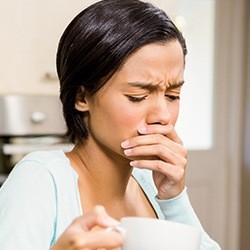 Woman in pain covering mouth before emergency dentistry