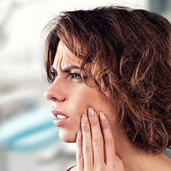 Woman with knocked out tooth holding cheek in pain