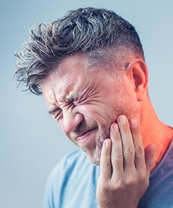 Man holding jaw in pain before tooth extraction