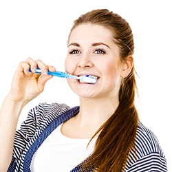 woman brushing for dental implant care in Assonet