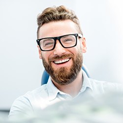 Bearded man with glasses smiling in dental chair