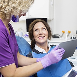 Dentist showing a patient dental implant information on a tablet