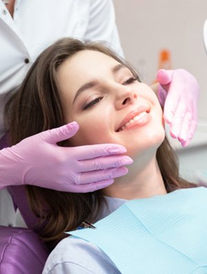 Woman in dental chair admiring her smile in mirror