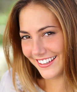 Woman smiling outside after metal free dental restoration
