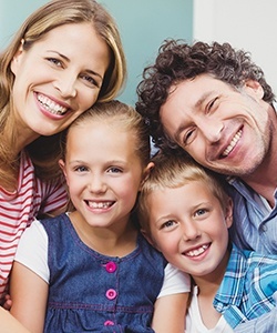 Mother father and two children smiling after preventive dentistry visit