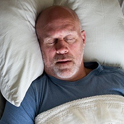 Man sleeping soundly in bed thanks to sleep apnea treatment
