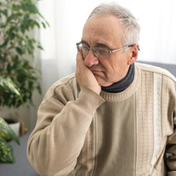 a man holding his cheek due to tooth pain