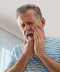 a an holding his cheek due to failed dental implant