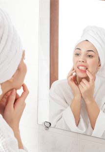 Woman looking at her teeth in bathroom mirror