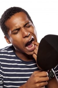 man looking at mouth in mirror