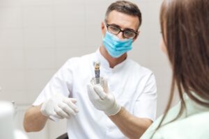 Dentist showing woman a model of a dental implant